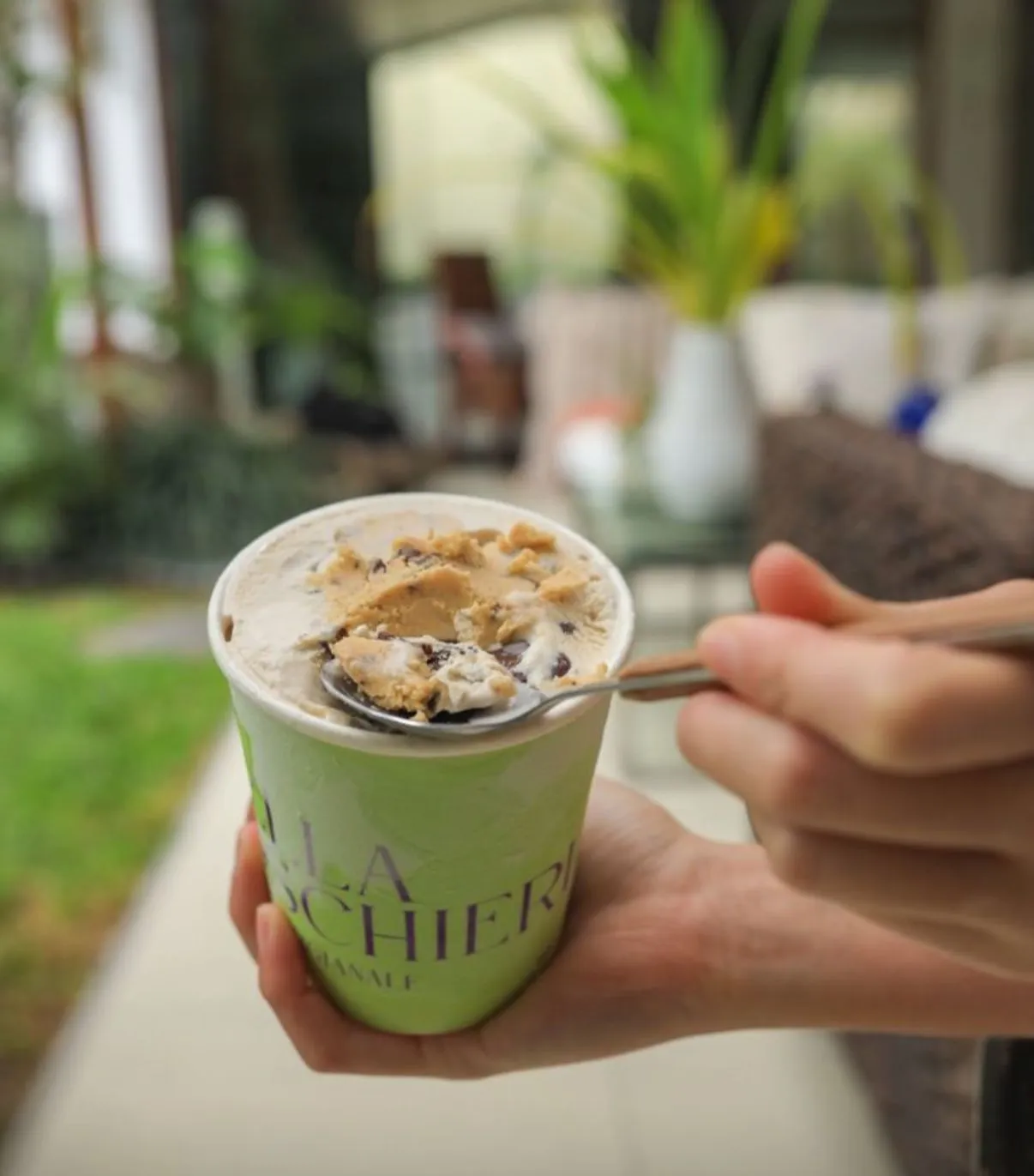 Pote de gelato cookie dough con una cuchara sirviendo un trozo de masa comestible