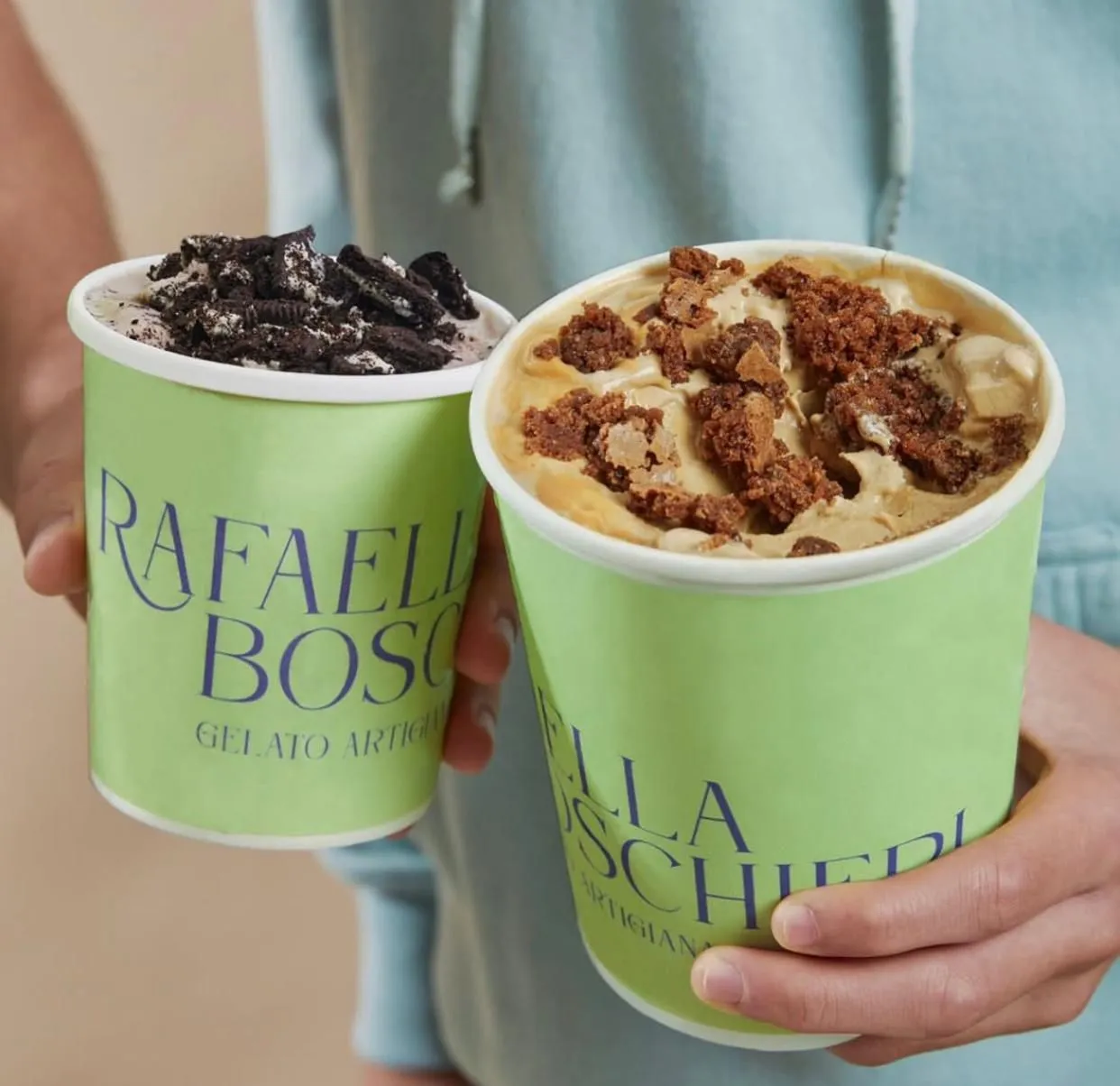 Una persona sosteniendo dos potes de gelato Rafaella Boschieri: cookies and cream y uno con trozos de brownie
